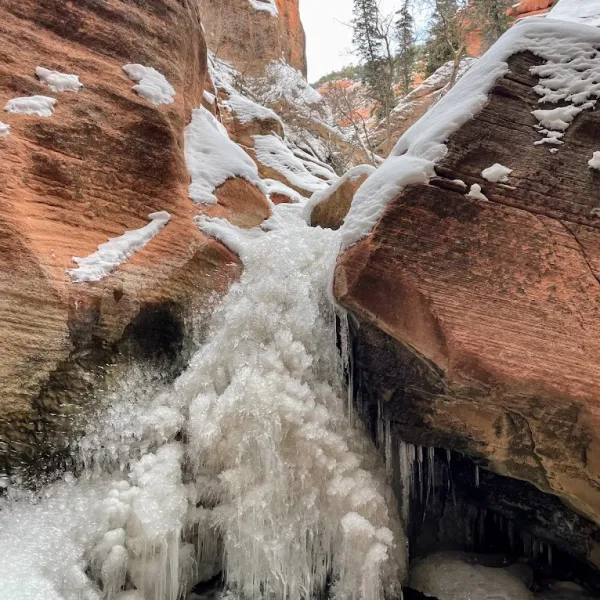 a pile of snow next to a waterfall