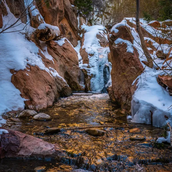 a pile of snow next to a waterfall